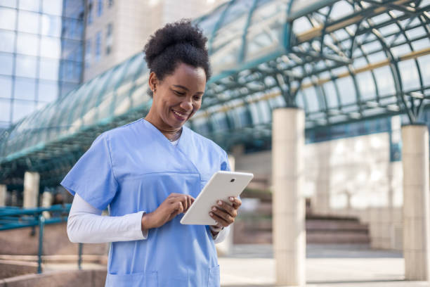 istock Smiling nurse using digital tablet outside hospital 2204901694