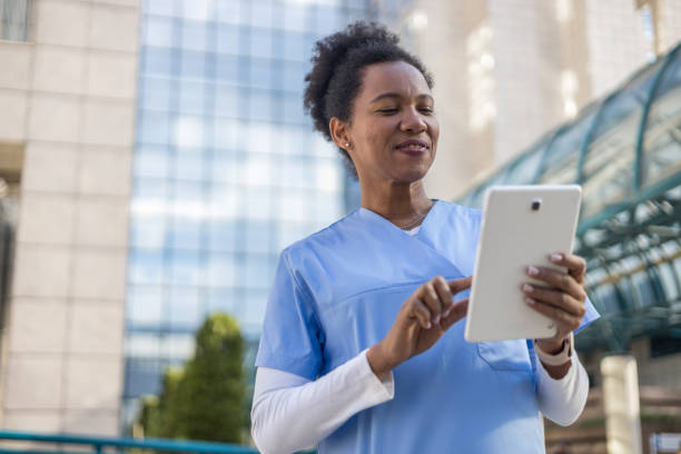 istock Smiling female doctor using digital tablet outside hospital 2204901709