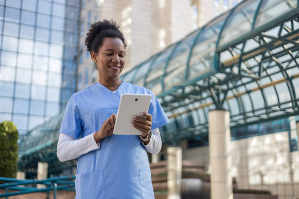 istock Smiling nurse using digital tablet outside hospital building 2204901741
