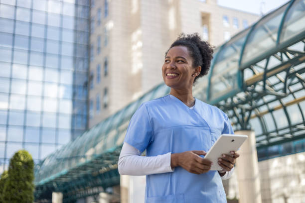 istock Smiling female doctor using digital tablet outside hospital building 2204901746