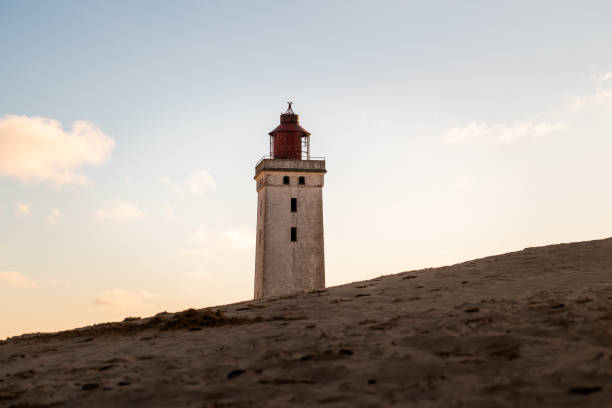 Rubjerg Knude lighthouse at coast with beautiful sea and horizon in background under clear blue sky during summer at Jutland, Denmark