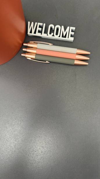 Three pens in a row on gray background, welcome sign above
