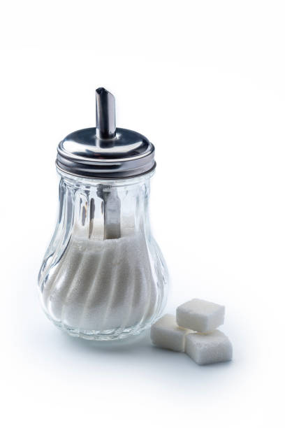 Close-Up Of Sugar Cubes In Spoon Over Tea Cup Against Blue Background