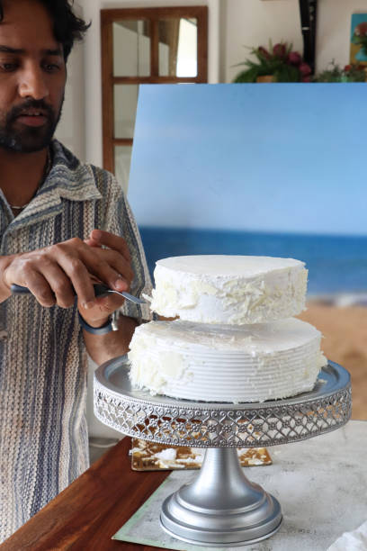 Closeup of an unrecognizable woman putting icing on a strawberry cake at a small family owned cake shop.