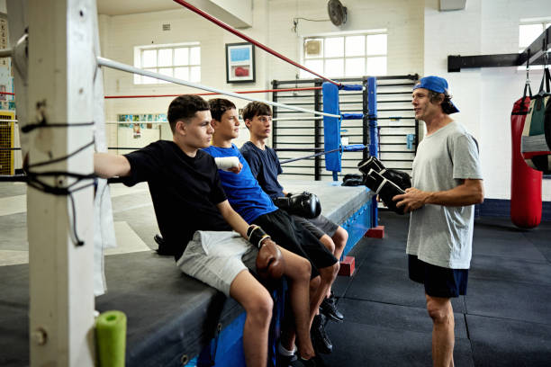 Trainer holding gloves and talking with young male boxers