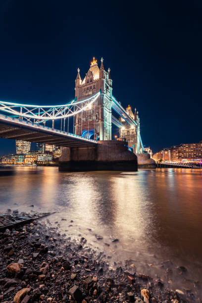 Stunning night view of Tower Bridge in London, UK, beautifully illuminated with city lights reflecting on the River Thames. A historic and iconic London landmark captured with the skyline in the background.