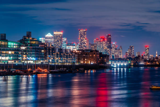 Breathtaking night view of canary wharf's illuminated skyscrapers reflected on the calm waters of the river thames in london