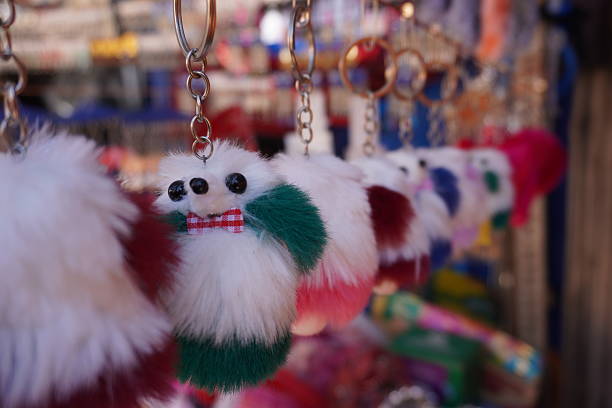 Green plush toy keychain centered on a red background. A nostalgic accessory from the past when many keys were needed to be on person. With copy space.