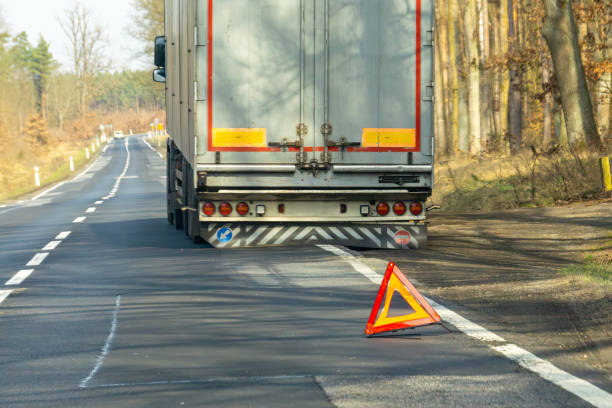 istock truck breakdown.broken truck with semi-trailer on national road. warning triangle displayed on the road. flat tire on semi-trailer. 2204911469