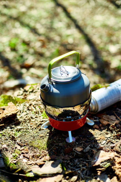 istock Outdoor kettle boiling water on portable stove in a serene forest setting during a sunny day 2204916449