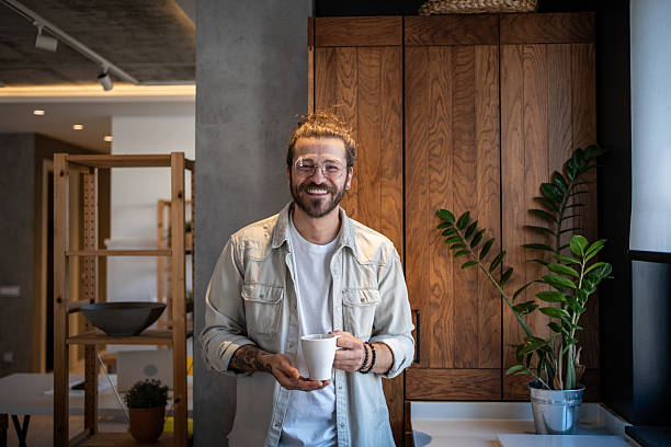istock Smiling freelancer enjoying a coffee break in his modern home office 2204916491