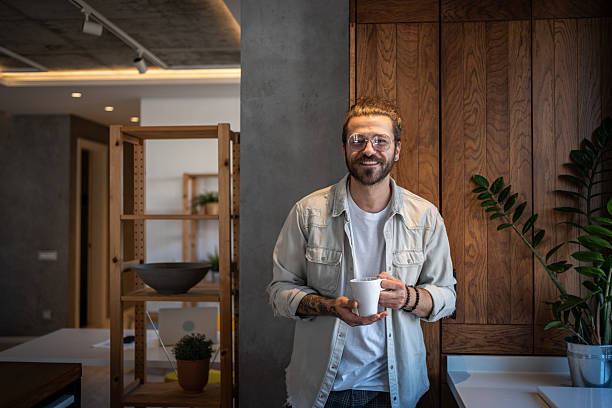 istock Young man smiling and holding a coffee mug in his modern apartment 2204916510