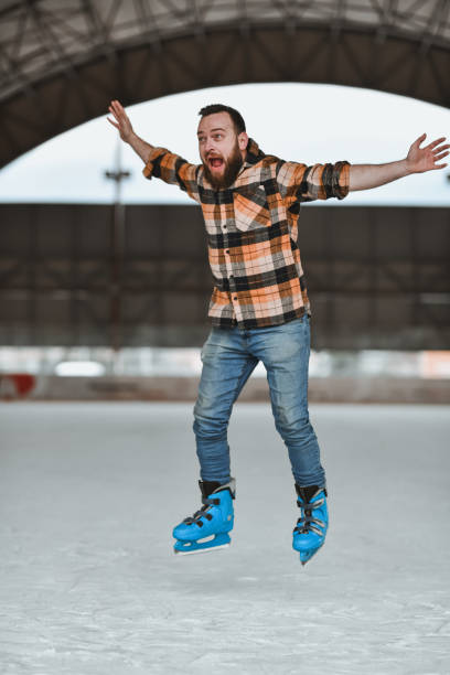 istock Male Ice Skating Instructor Jumping on Ice Rink Raising Arms and Shouting 2204918319