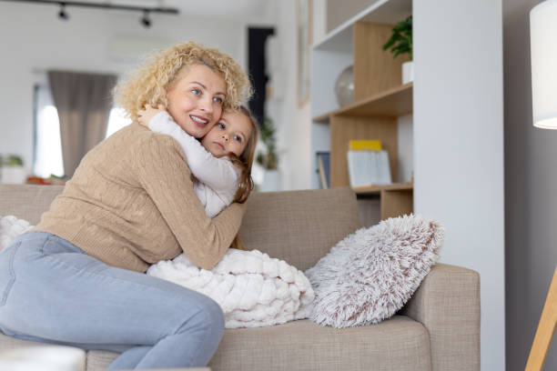 istock Mother Embracing Daughter Under Blanket with Care 2204919909