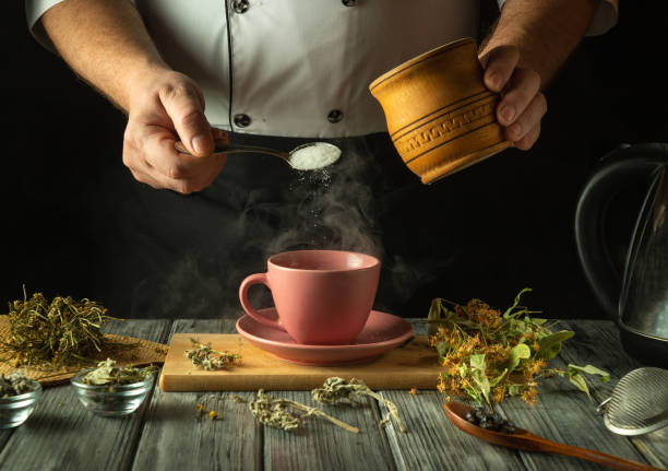 istock A skilled chef gently adds sugar to a pink teacup filled with steaming herbal tea. Fragrant dried herbs surround the cup, creating a warm, inviting atmosphere in a rustic kitchen 2204920257