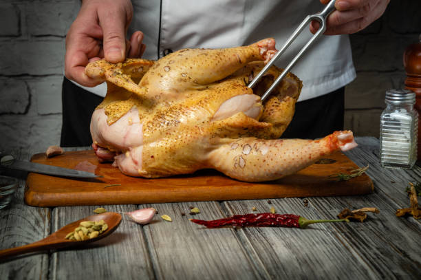 istock A skilled chef skillfully prepares a whole chicken on a wooden cutting board, surrounded by fresh ingredients and tools. The atmosphere is warm, evoking the joy of home cooking 2204920955