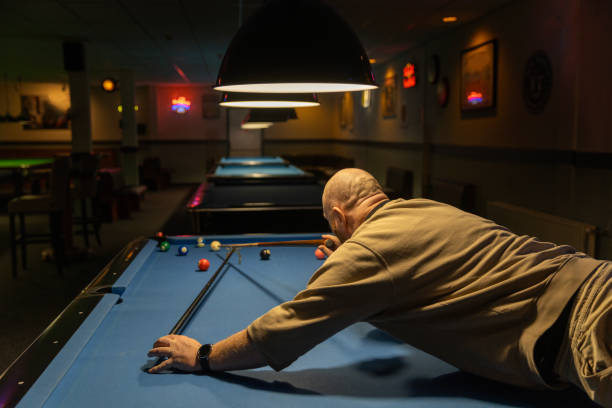 Stylish senior redhead man playing pool in a public bar