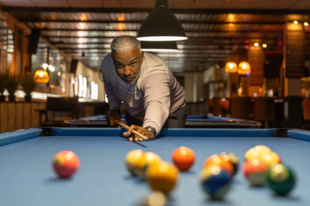 Stylish senior black man playing pool in a public bar