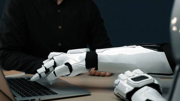 istock Futuristic robotic arm interacts with laptop on modern office desk showcasing advanced technology and human-like design in artificial intelligence environment. Noogenesis 2204925131