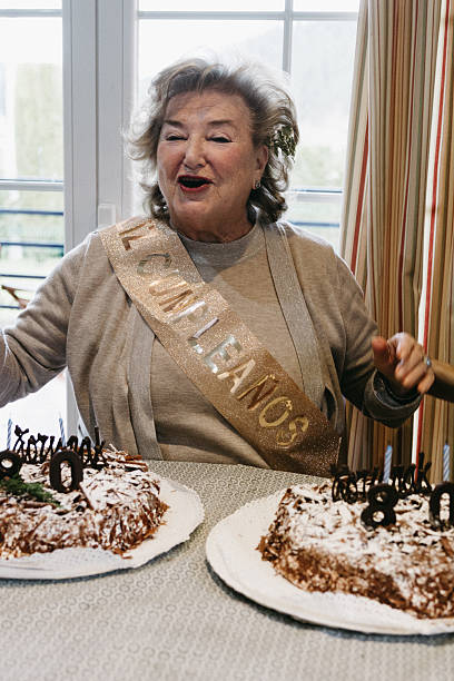 istock Joyful elderly woman singing with two birthday cakes 2204925253