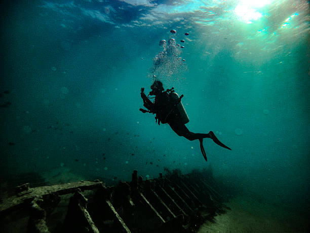 Scuba Diver Exploring a Mysterious Shipwreck in the Deep Ocean