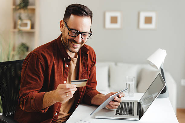 istock Happy male is making an online payment using his credit card and digital tablet 2204925630