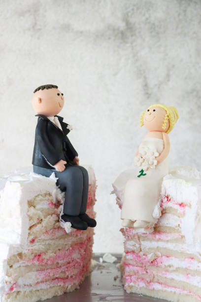 istock Image of wedding cake sliced with bride and groom figurines, smooth fondant icing, presented om silver cake stand 2204926607