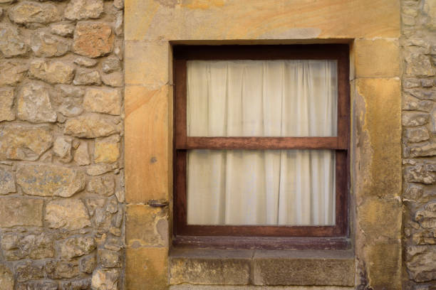 istock White curtain in wIndow in stone house facade 2204927119