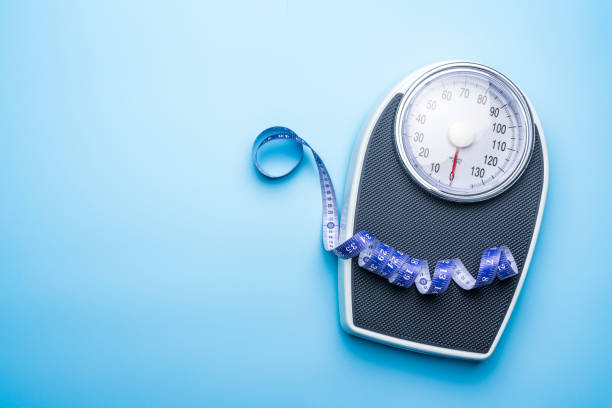 istock Bathroom scale and measuring tape on blue background with copy space. Weight control, exercising  and wellbeing concept 2204939923