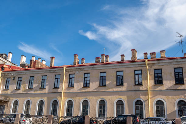 A well-preserved historic building showcases its distinct chimney details and large windows under a bright blue sky in Saint Petersburg.
