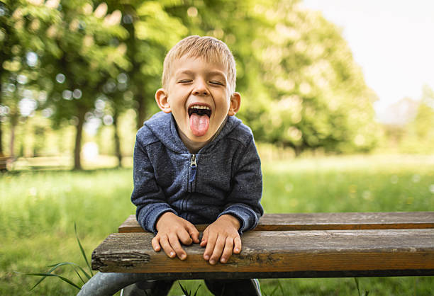 Little silly boy showing his tong to the camera in the park.