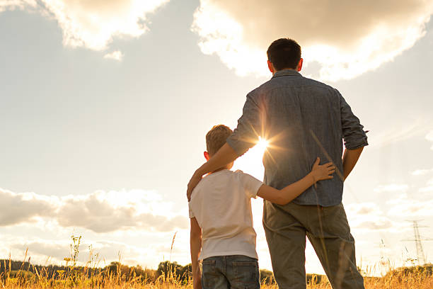 istock Father and son watching beautiful sunset together. 2204942625