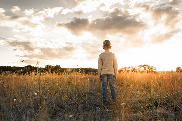 istock Child watching the sunset feeling at peace in nature. 2204942750