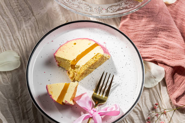 istock Mousse cake with pink velour, mango mousse and passion fruit in a cut on a glass cake plate. Low-calorie mousse dessert. Cake with mango mousse and passion fruit. Side view. Flatlay. High quality photo 2204947295