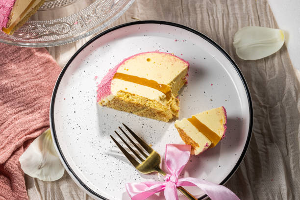 istock Mousse cake with pink velour, mango mousse and passion fruit in a cut on a glass cake plate. Low-calorie mousse dessert. Cake with mango mousse and passion fruit. Side view. Flatlay. High quality photo 2204947297