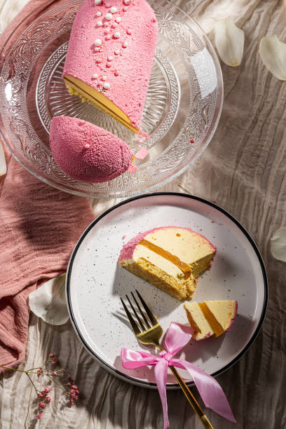 istock Mousse cake with pink velour, mango mousse and passion fruit in a cut on a glass cake plate. Low-calorie mousse dessert. Cake with mango mousse and passion fruit. Side view. Flatlay. High quality photo 2204947298