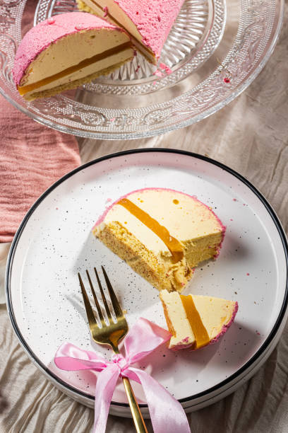 istock Mousse cake with pink velour, mango mousse and passion fruit in a cut on a glass cake plate. Low-calorie mousse dessert. Cake with mango mousse and passion fruit. Side view. Flatlay. High quality photo 2204947301