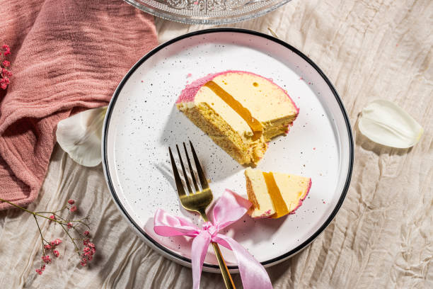 istock Mousse cake with pink velour, mango mousse and passion fruit in a cut on a glass cake plate. Low-calorie mousse dessert. Cake with mango mousse and passion fruit. Side view. Flatlay. High quality photo 2204947303