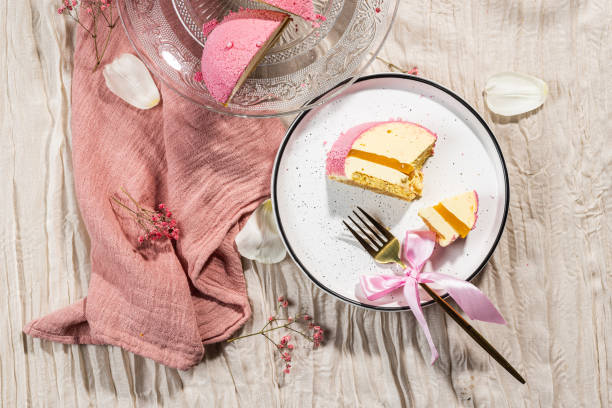 istock Mousse cake with pink velour, mango mousse and passion fruit in a cut on a glass cake plate. Low-calorie mousse dessert. Cake with mango mousse and passion fruit. Side view. Flatlay. High quality photo 2204947311