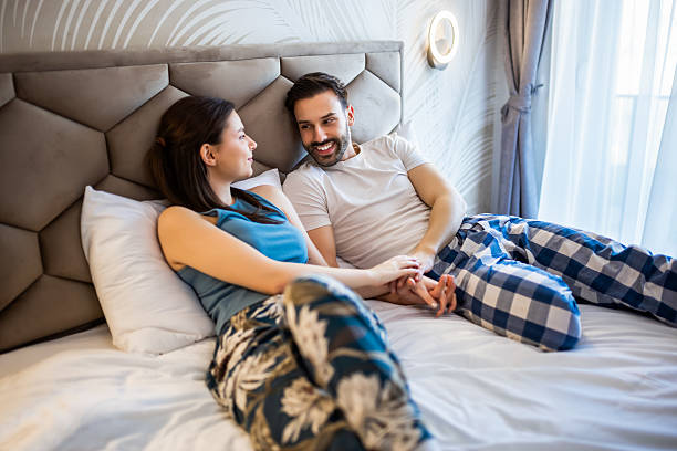 istock Lovely young couple hold hands in bed and talk. 2204949384