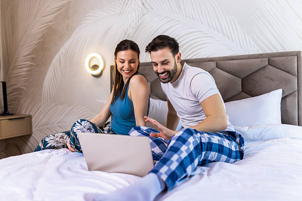 istock Couple in pajamas in bed using their laptop. 2204950809
