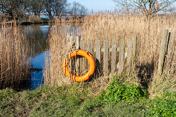 Orange life saver ring in a prominent and accessible place on the river bank of Horsey Mere. Captured on a bright and sunny morning