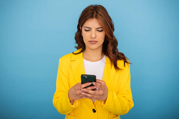 istock Young businesswoman using smartphone, looking at the screen with a serious expression 2204958963