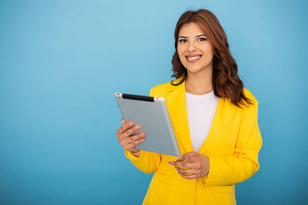 istock Young businesswoman smiling and using a digital tablet on blue background 2204959618