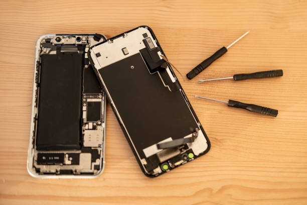 istock Smartphone repair process with screwdriver and disassembled mobile phone on wooden table. Tech service concept, technical support, service center, display replacement 2204959999