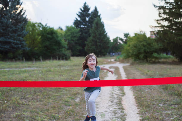 istock Cheerful child runner crossing finish line in a race competition 2204964009