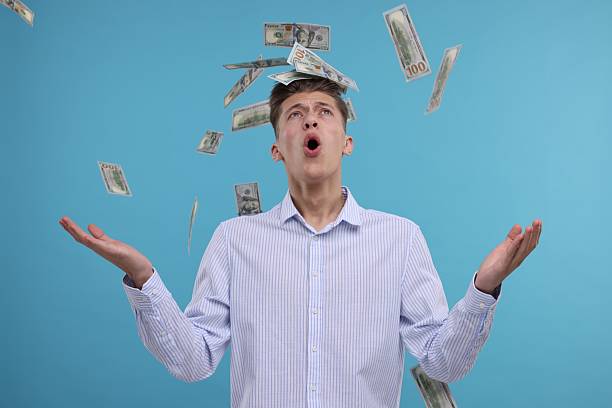 istock Handsome man under money shower on light blue background 2204965884