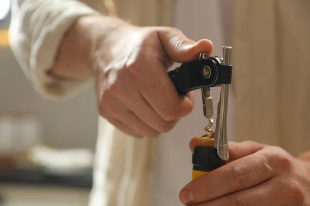istock Man opening wine bottle with corkscrew on blurred background, closeup 2204967205