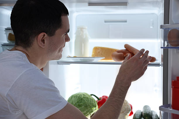 istock Man taking sausages out of refrigerator at night 2204967277