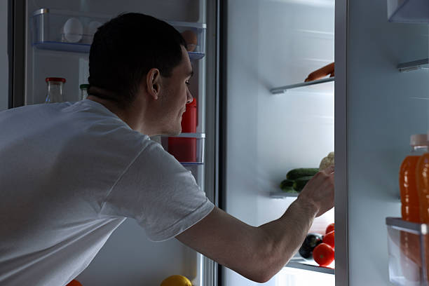 istock Man near refrigerator in kitchen at night 2204967280